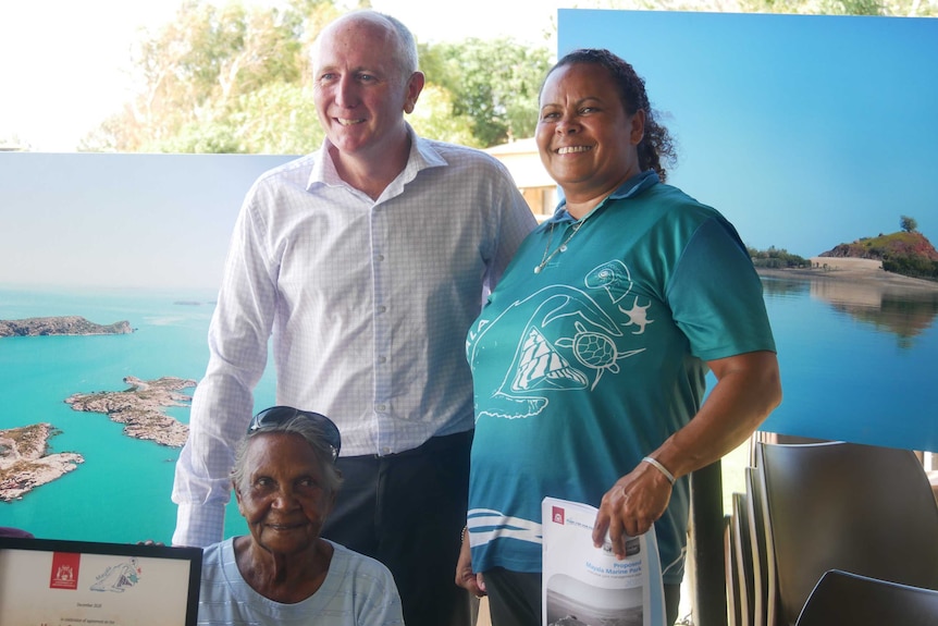 Two women and a man stand in front of Buccaneer Archipelago posters