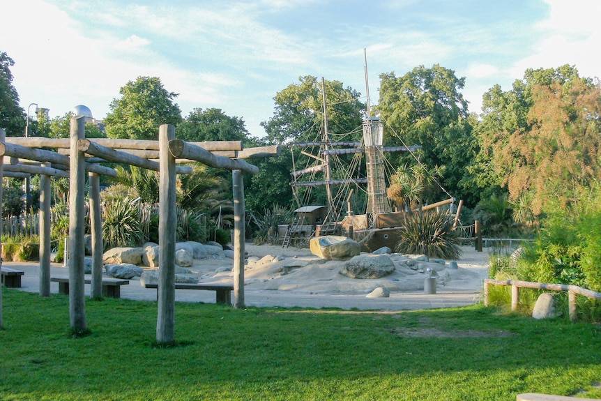 A playground featuring a big wooden pirate ship and monkey bars