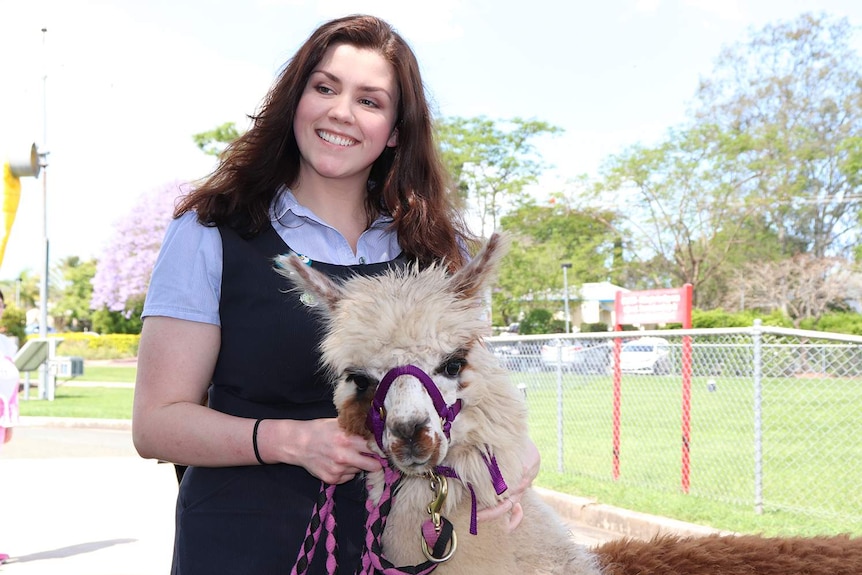 Registered midwife Talitha Kirk smiles as she holds therapy alpaca Pancake outside Beaudesert hospital.