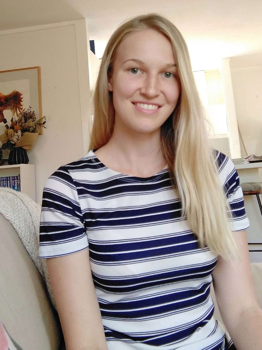 A blonde haired woman sits on her lounge.