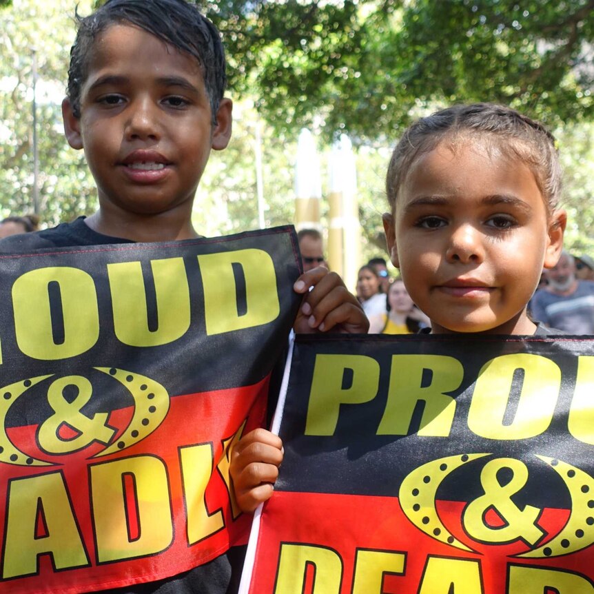 Two children holding Aboriginal flags that read "proud and deadly".