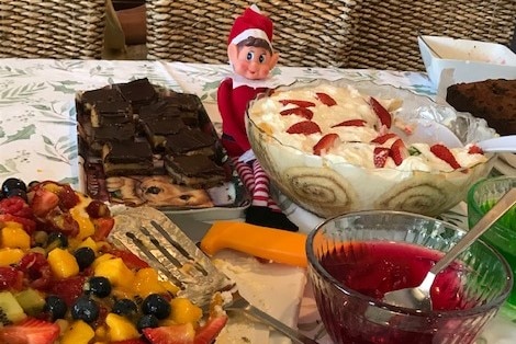 An elf among trifle and chocolate desserts.