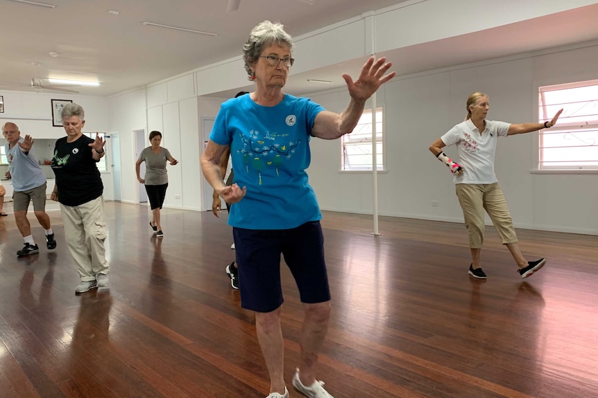 Arms outstretched as members of a tai chi class go through the motions in CWA hall