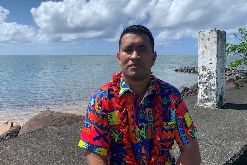 A Samoan man in a bula shirt by the ocean
