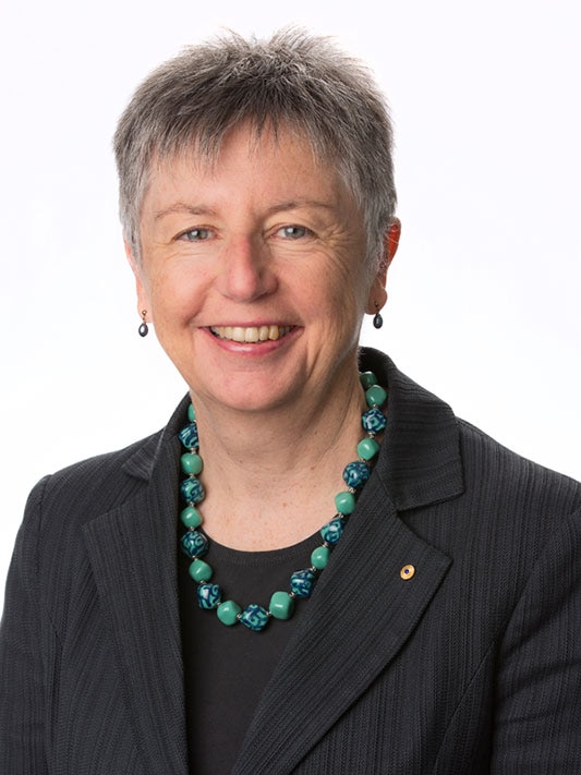 A woman with short grey hair smiles for the camera.