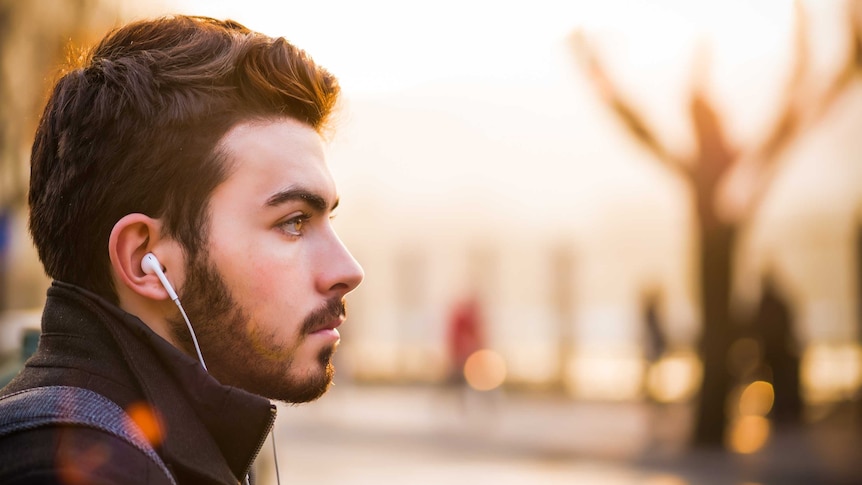 man wearing earbuds gazing into the distance