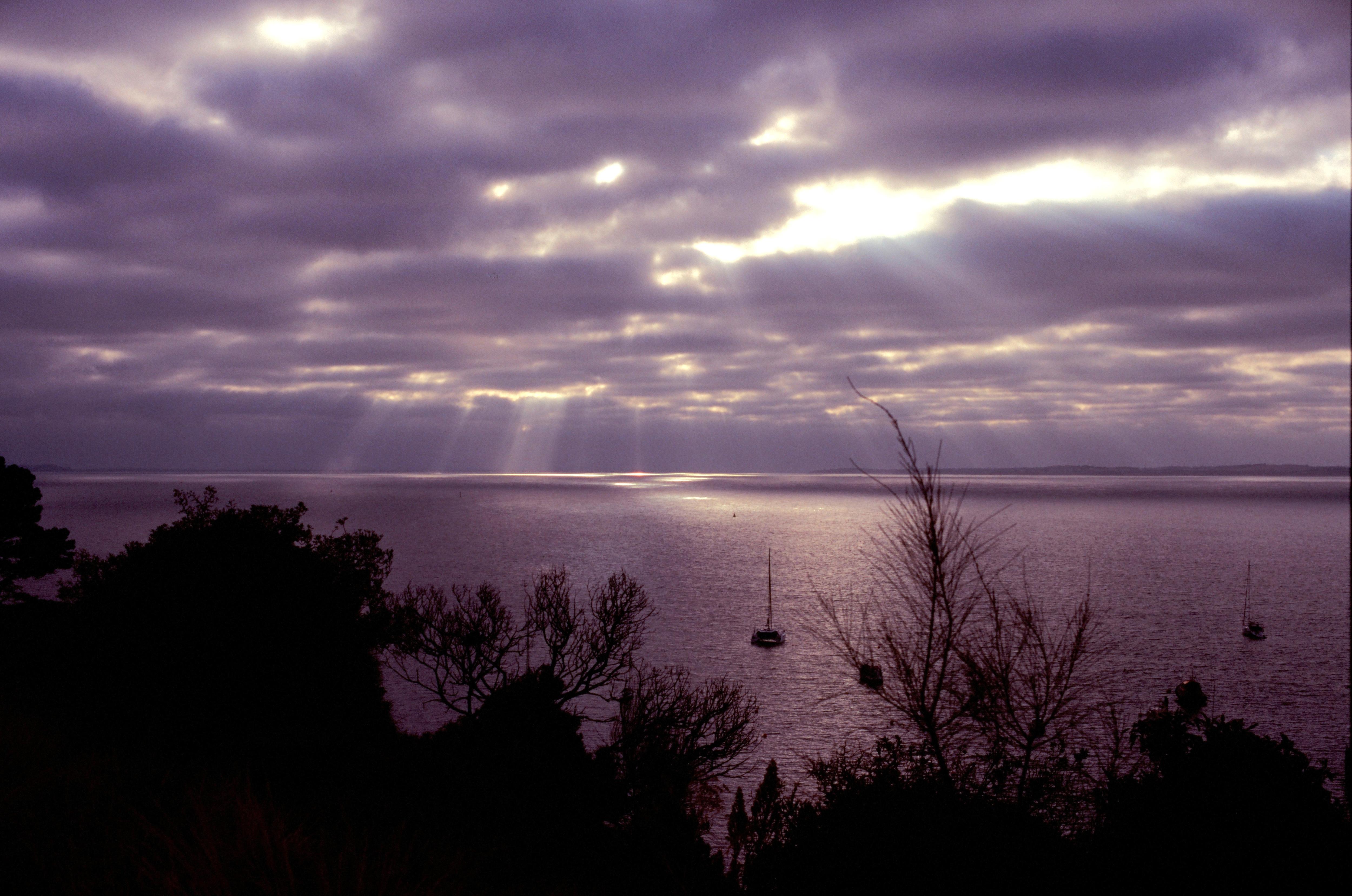 El sol atraviesa las nubes sobre una tranquila vista del mar. 