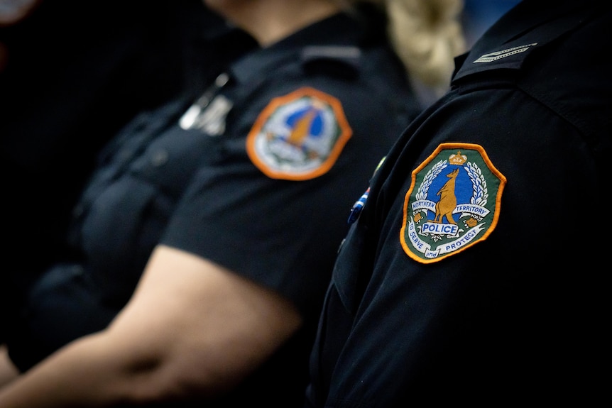 Two police officers sit side by side. Their faces are cut out. 