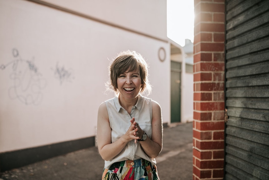 Photographer Breeana Dunbar stands in an alleyway laughing at the camera, and is proud of her life as a single mum.