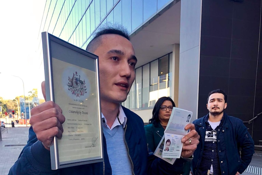 Sadam Abudusalamu holds his son Lutfy's Australian passport and citizenship certificate outside Marise Payne's office.