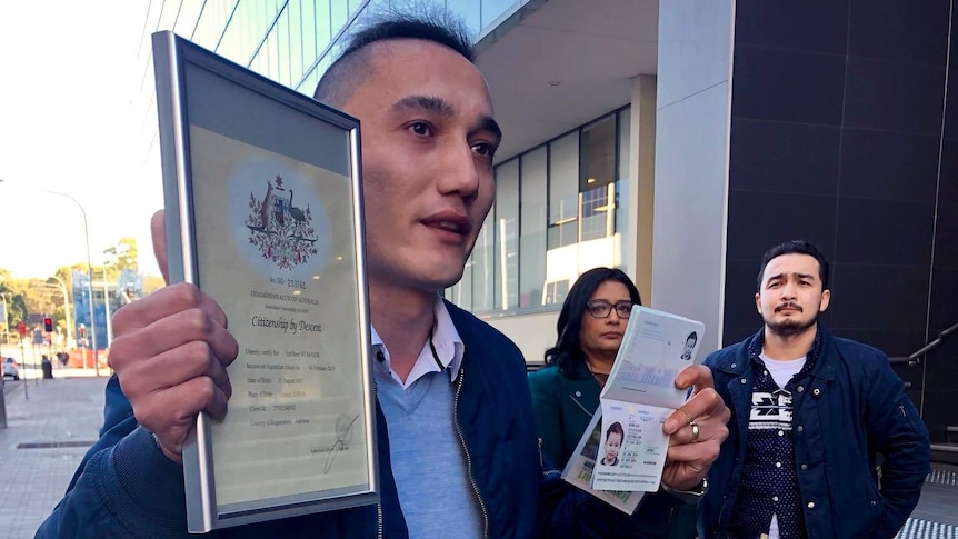 Sadam Abudusalamu holds his son Lutfy's Australian passport and citizenship certificate outside Marise Payne's office.