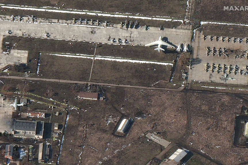 Planes on an airfield with dark spots and smoke arising