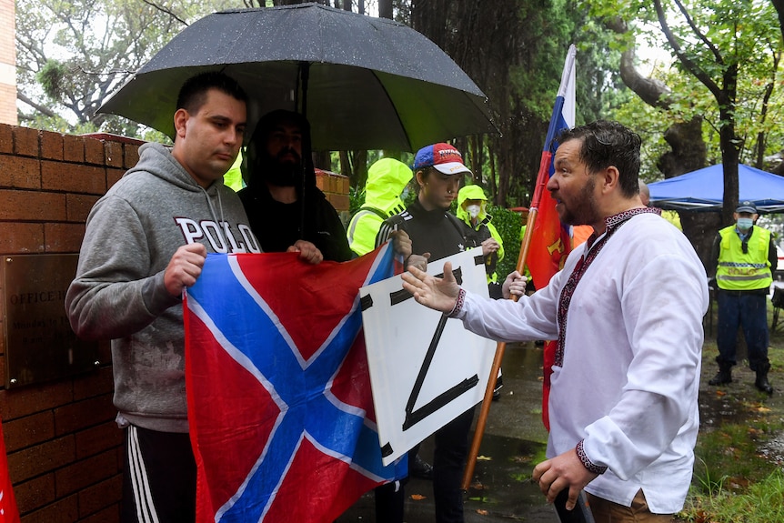 A man yells toward another man holding a sign