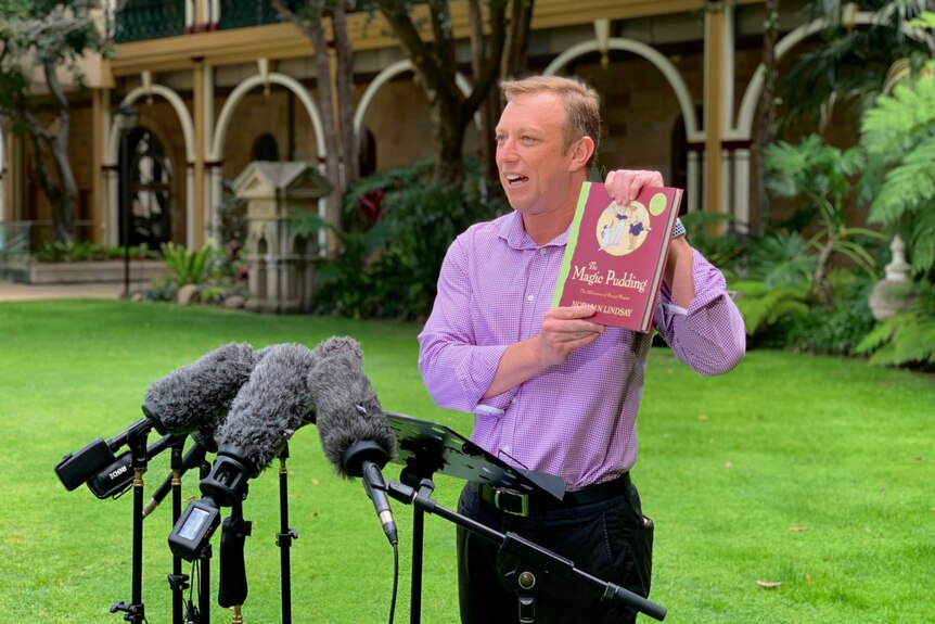 Miles holding a book up to the media