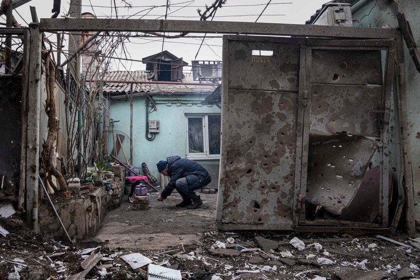 A man crocuhes down amoungst the remains of house after an air strike