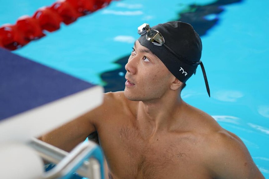 A swimmer in a pool in a cap and goggles.