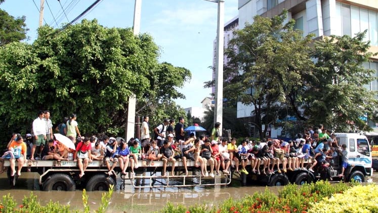 People crowd onto the back of a truck as it drives through a flooded Bangkok street on October 18, 2011.