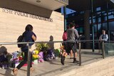 NSW police employees walk past floral tributes at Parramatta Police HQ