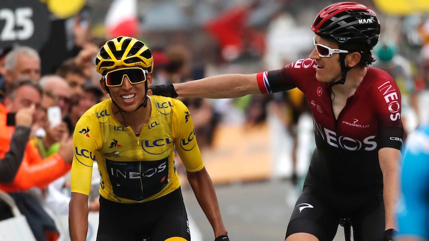 Geraint Thomas pats Egan Bernal on the back while they ride side by side