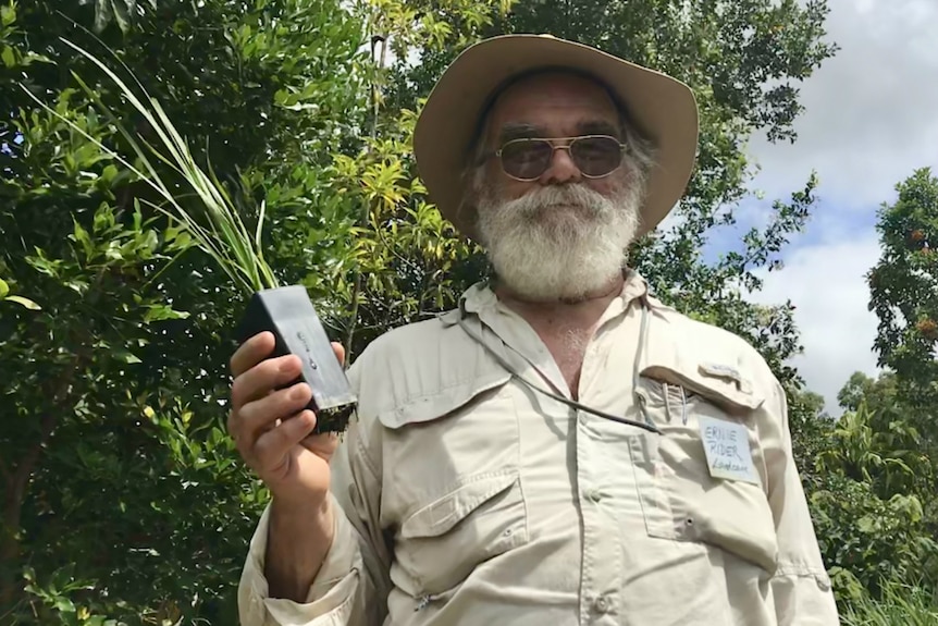 A bearded man wearing a hat and sunglasses holds a tubestock.