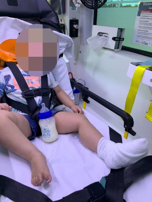 The two year old boy in the ambulance with eyes closed and bandaged foot.