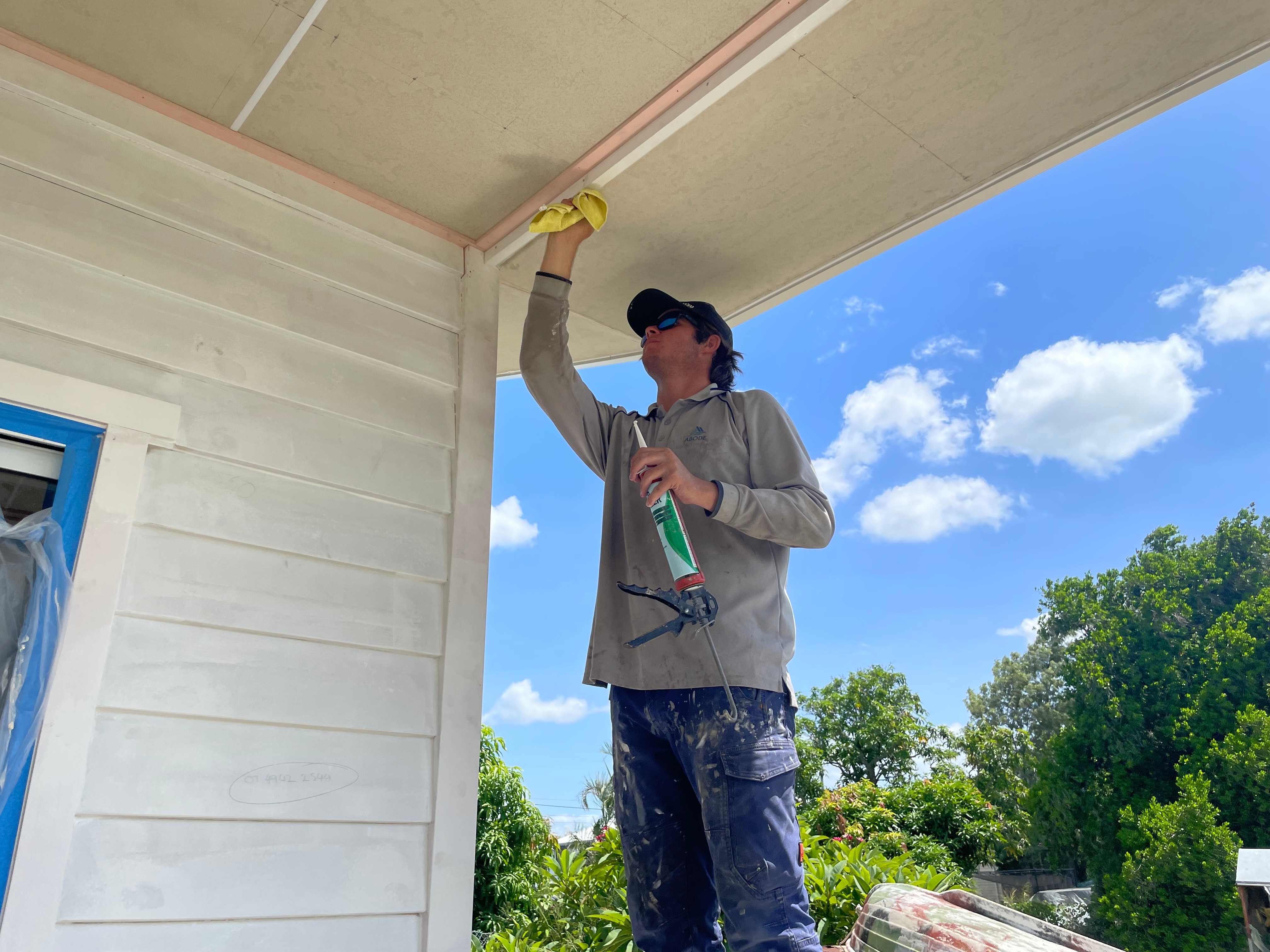 Man with rag wipes away excess spac filler on a ceiling.