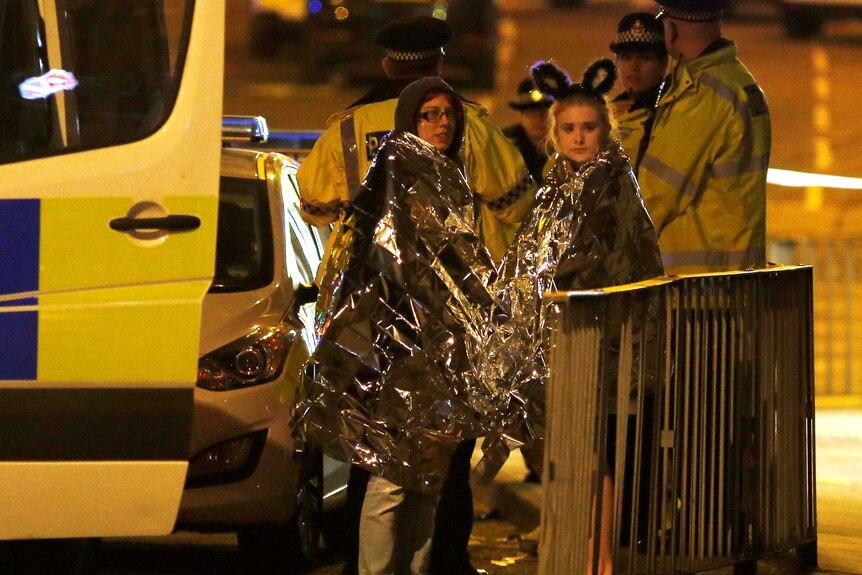 Two women wrapped in thermal blankets stand near the Manchester Arena in northern England, Britain