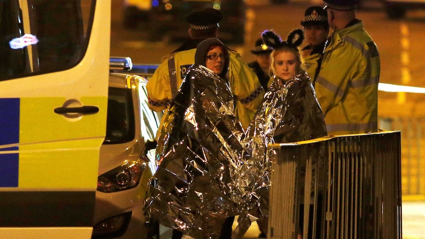 Two women wrapped in thermal blankets stand near the Manchester Arena in northern England, Britain