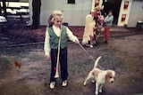 A young Rebel Wilson stands with a dog on a lead.