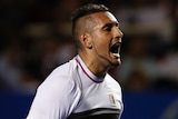 Nick Kyrgios screams in delight while holding his racquet.