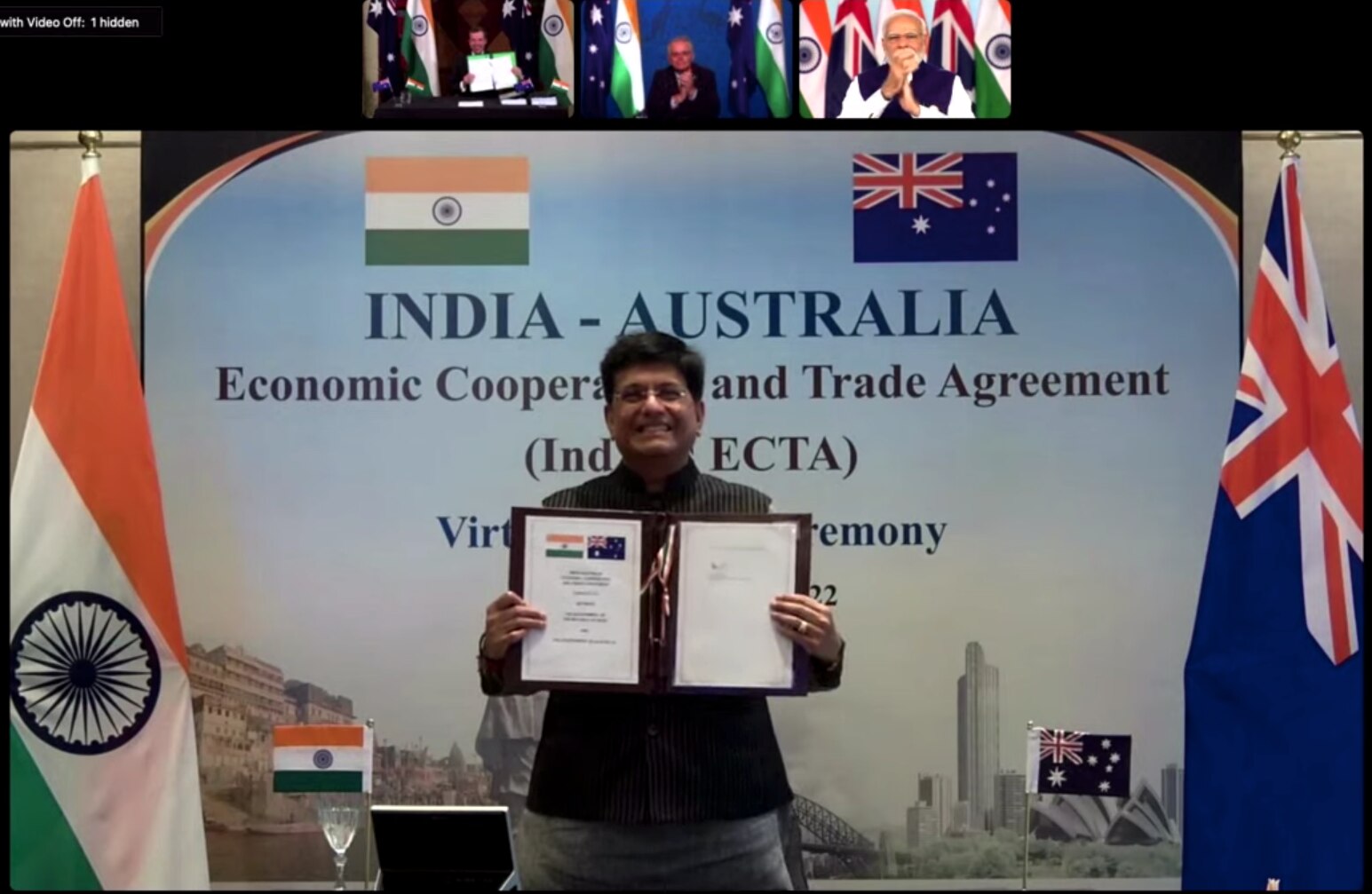 India's trade minister holds up a signed document. In other screens, Tehan does the same and Morrison and Modi applaud