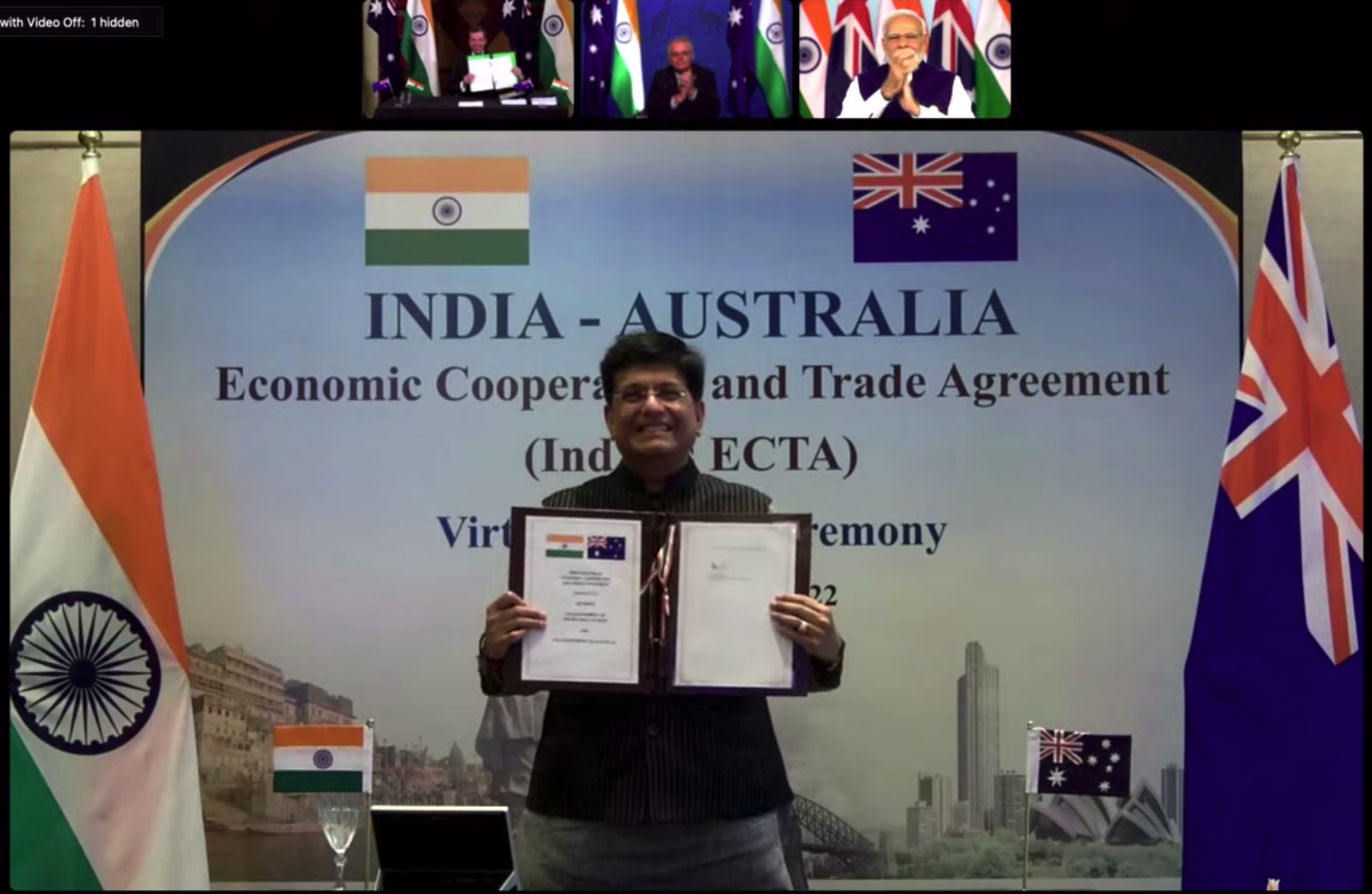 Le ministre indien du commerce brandit un document signé.  Sur d'autres écrans, Tehan fait de même et Morrison et Modi applaudissent
