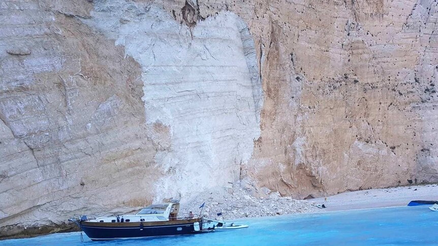 Small boats are capsized in the water at a Greek beach after a landslide.