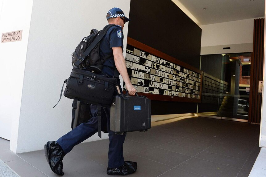 Police forensics officer enters a Teneriffe apartment block in Brisbane on October 6, 2014.