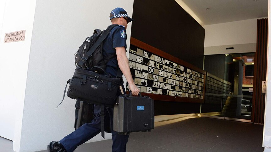 Police forensics officer enters a Teneriffe apartment block in Brisbane on October 6, 2014.