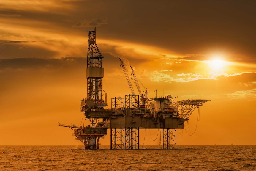 A offshore oil rig platform silhouetted at sunset