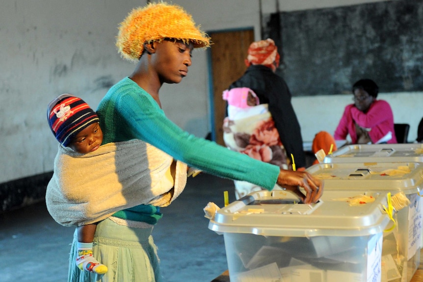 A Zimbabwean mother holding her child casts her ballot in Domboshava.