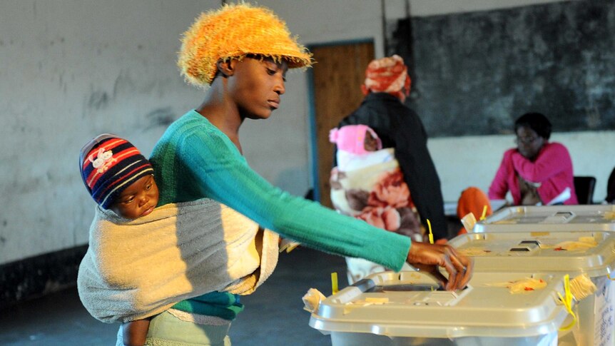 A Zimbabwean mother holding her child casts her ballot in Domboshava.