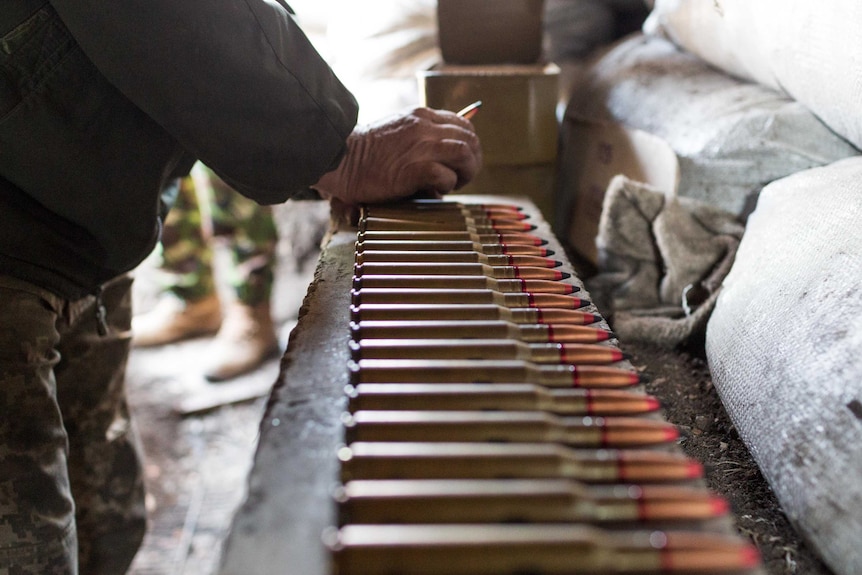 A soldier reloads bullets into his heavy machinegun.