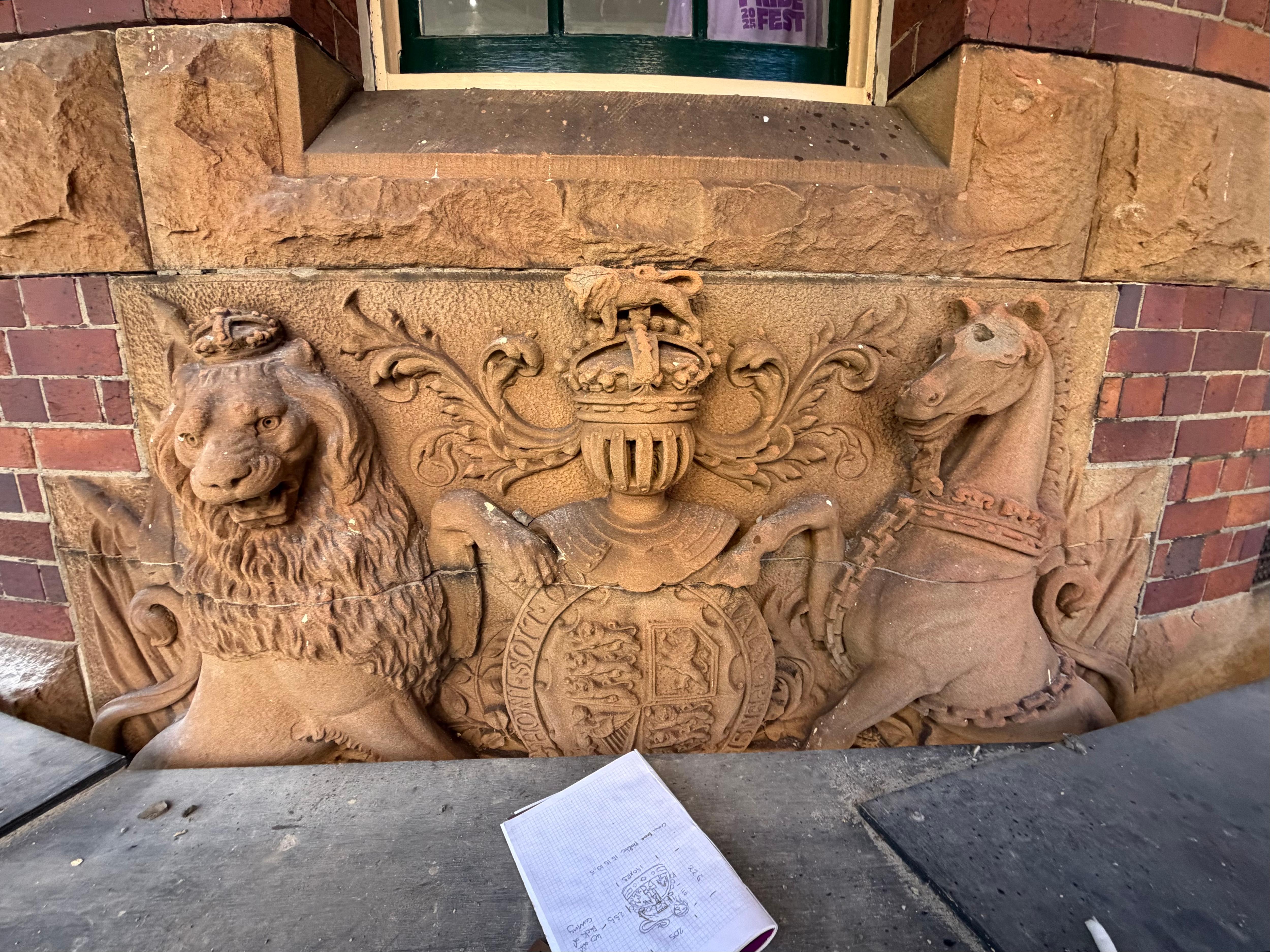a sandstone coat of arms of a dragon and horse with a eroded lion