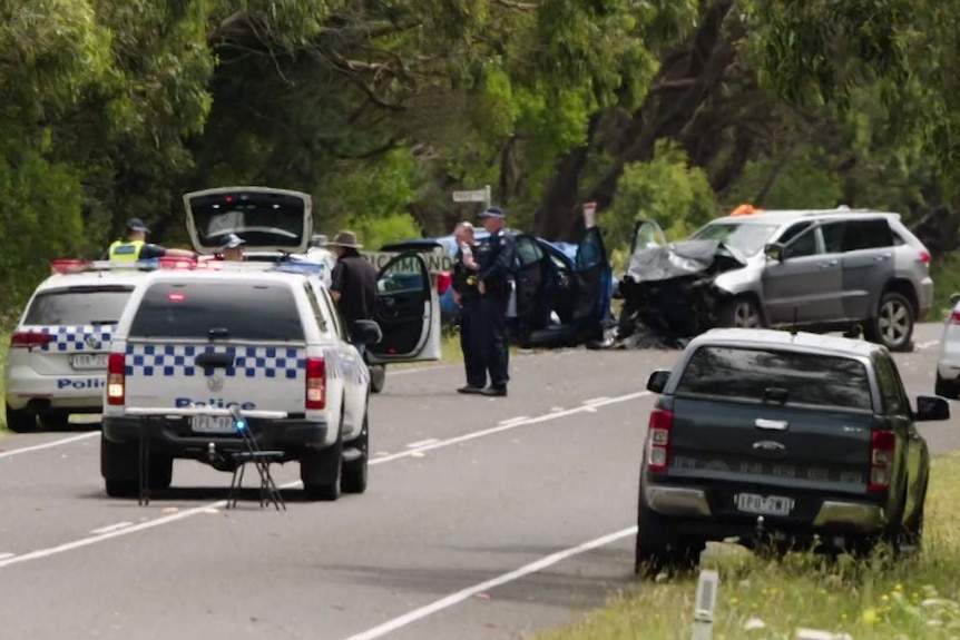 A silver Jeep 4WD and a blue holden hatchback are crumpled after a crash. Three police cars are at the scene.