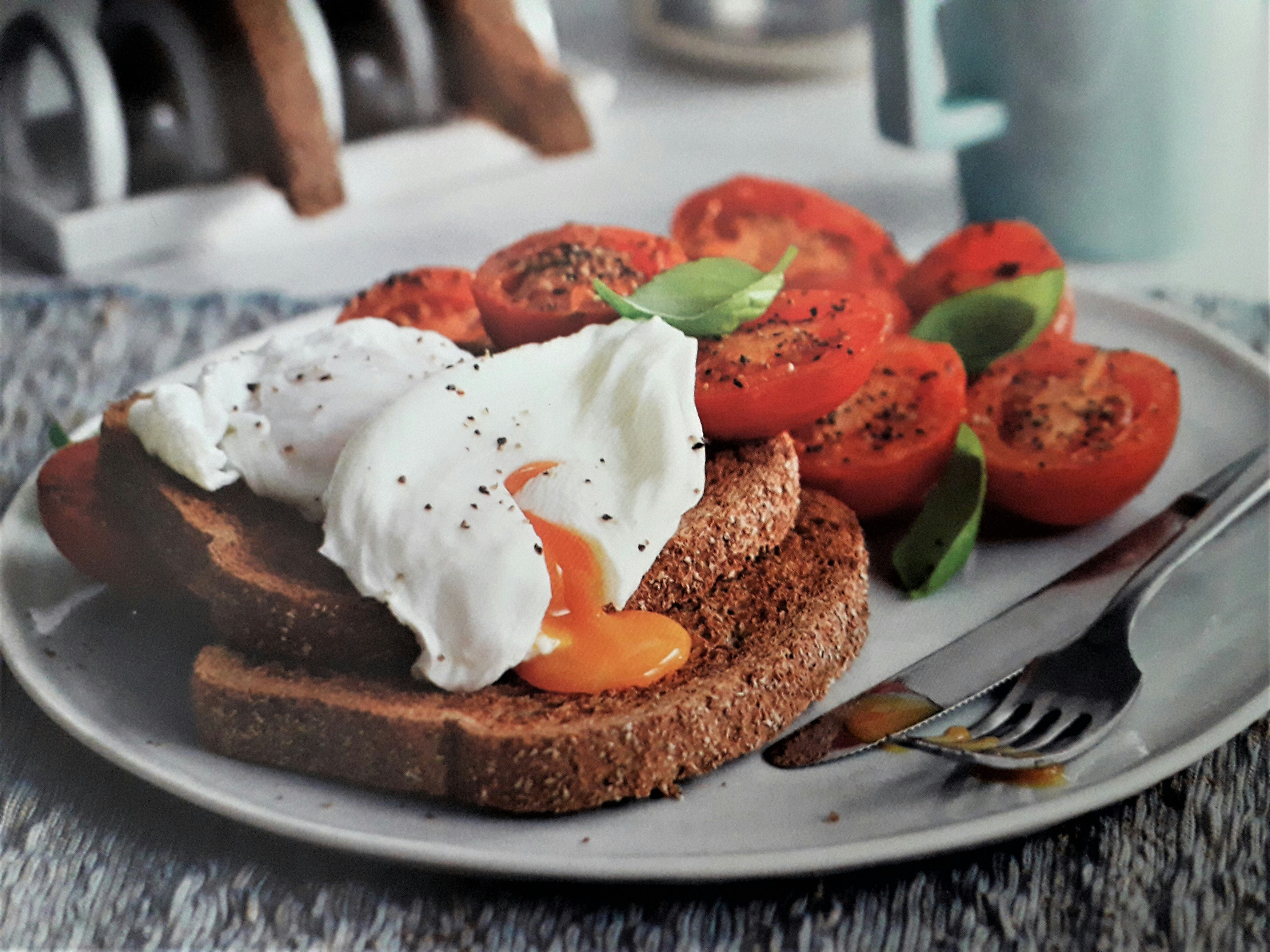 Runny paoched eggs on toast with tomato.