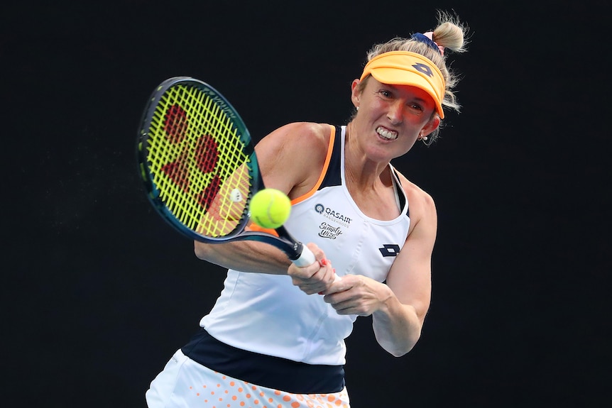 An Australian female tennis players hits a backhand.