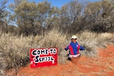 A termite mound wears a school uniform next to sign reading 'Come to school'