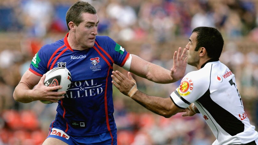 Chris Houston of the Newcastle Knights fends off the Warriors' Stacey Jones