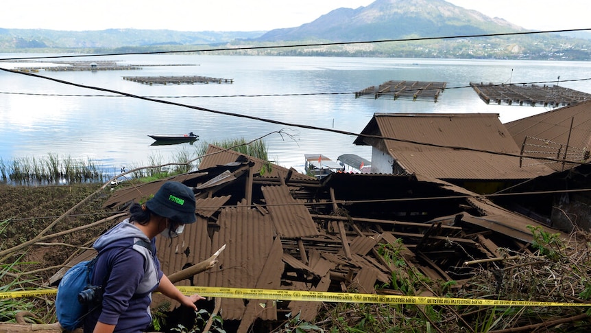 A woman walks past houses by Lake Batur which were damaged by an earthquake-triggered landslide in Bangli.