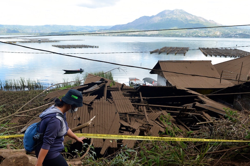A woman walks past houses by Lake Batur which were damaged by an earthquake-triggered landslide in Bangli.