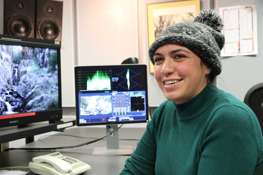 Producer wearing beanie sitting at desk.