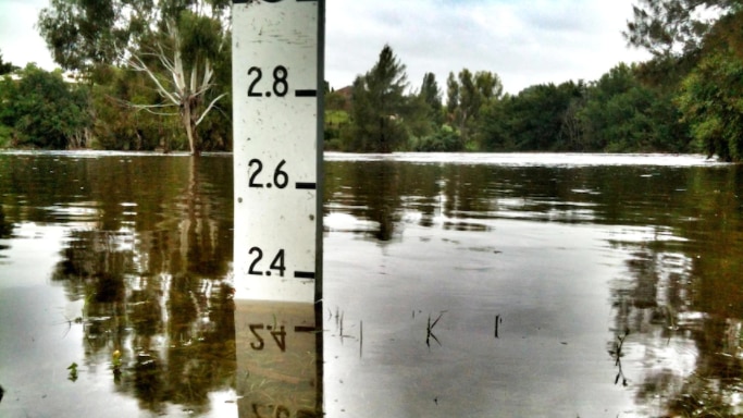 Water measures at 2.4 metres on a flood reading post.