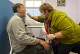 A female nurse takes an oral swab from a male patient.